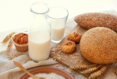 Süt, ekmek, kek, bisküvi, bir tabak kepek, dikenli dikenler ve dağınık poldba taneleriyle dolu bir hayat. Kenevir kumaşında ve beyaz bir arka planda..