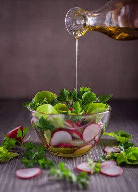 İçinde bitki, sebze ve bitki karışımı cam bir kasede salata. Yemek zeytinyağıyla tatlandırılmış..