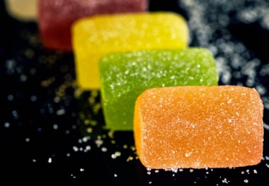 Çok renkli jöle şekerleri siyah bir zemine serpiştirilir..