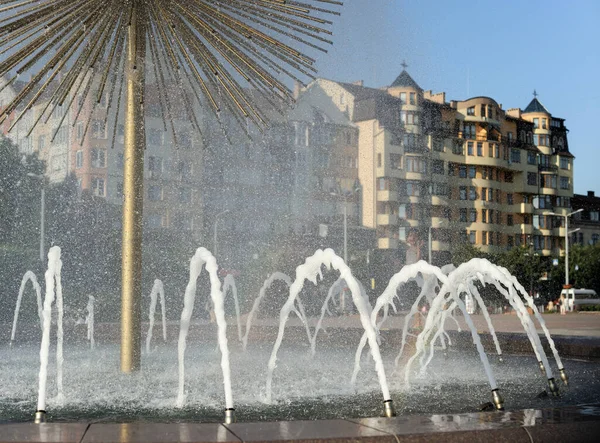 Fountain in the form of dandelion against the backdrop of buildings.
