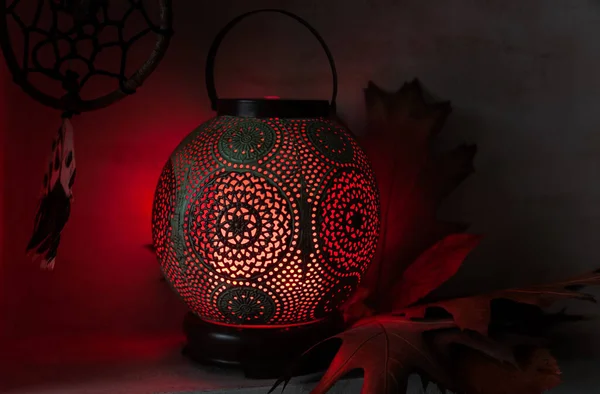 Aroma diffuser in the style of an ancient oriental lamp. Still life with a diffuser, a catcher of dreams and maple leaves.