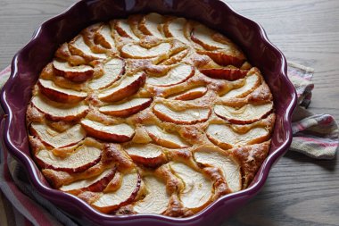 Tahta bir yüzeyde seramik bir kasede elmalı turta..