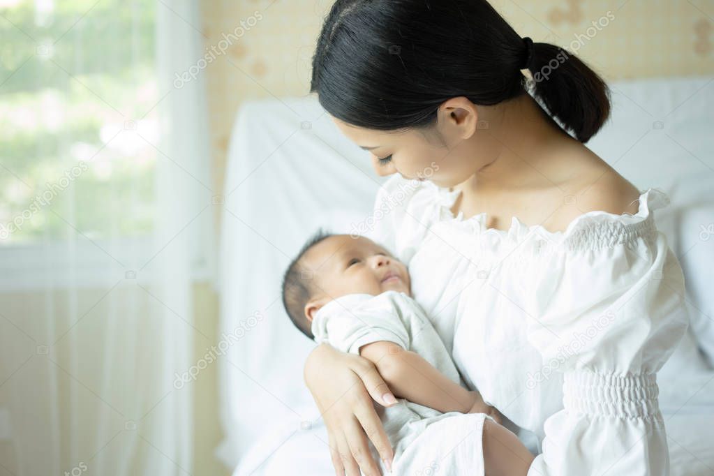 Young mother holding newborn baby, maternity concept, soft image of beautiful family