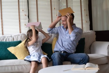 Mutlu babalar günü. Baba ve onun kızı oturma koltuk başları bir kitap ile gülümseyen komik portresi.