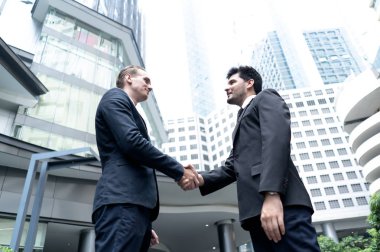 Modern ofis binası dışında el sıkışan iki yakışıklı iş adamı. Ortaklık ve ilgili kavramlar.