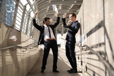 İki yakışıklı iş ayakta mutlu adam ve başarı sokak, kentsel arka plan etrafında kutlamak. Zaferi kazanan başarılı kurumsal ekibi, heyecanlı