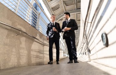 İki yakışıklı işadamı konuşma ve yürüme yolu, kentsel arka plan şehir holding kahve.