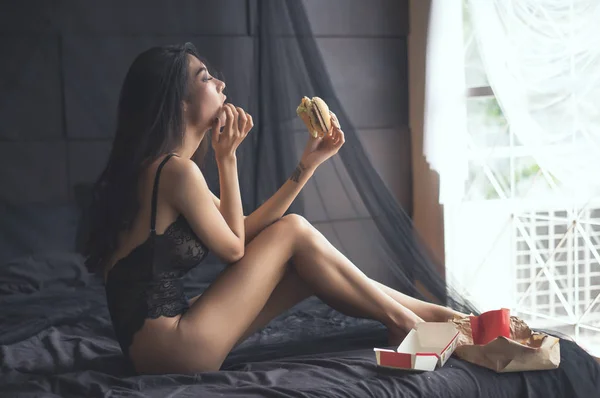 아시아 침대에 앉아서 햄버거를 속옷에 감량입니다 — 스톡 사진