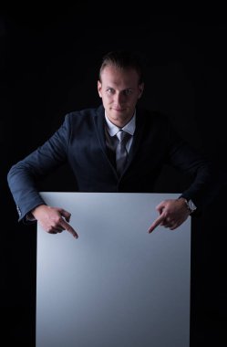 Siyah bir arka plan üzerinde boş billboard aşağı bakacak ve kameraya bakarak işadamı