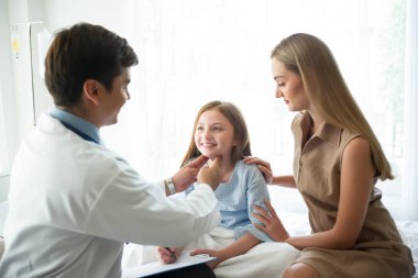 Doktor küçük kız ve annesi destek bebek onun elinde incelenmesi.