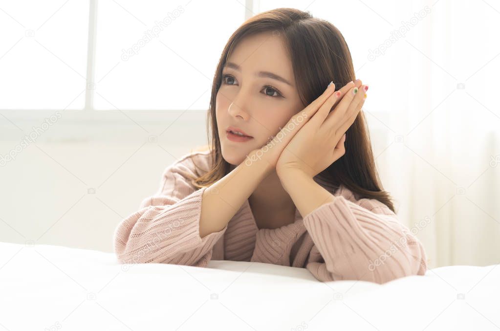 Portrait of a beautiful young Asian woman smiling, with hands on her face. Beauty and Winter concept.