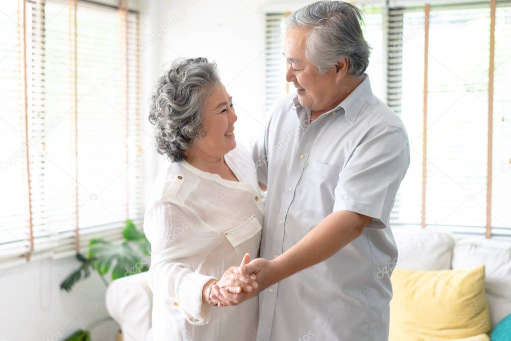 Beautiful senior couple smiling in love dancing at home.Happy life