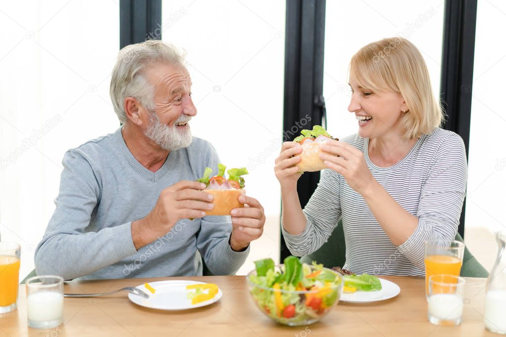 Happy senior couple enjoying eating breakfast together at home. Retirement Lifestyle Concept.