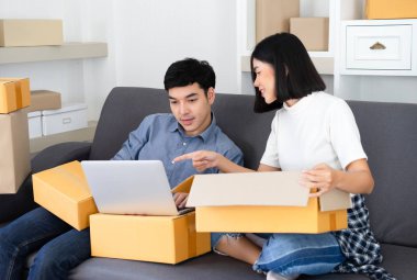 Online bir dizüstü bilgisayar kullanarak onu ambalaj Genç Asyalı Çift rahat çalışma küçük işletme. Birbirlerine bakıyor ve gülümsüyor. Genç iş evde iş sahibi. Küçük iş sahibi kavramı.