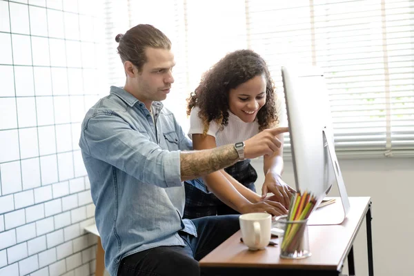 Happy couple doing business together working at small office with desktop computers.