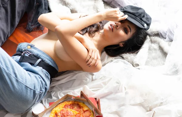 Wanita seksi dengan celana jeans biru tergeletak di lantai dengan kotak pizza dan e — Stok Foto