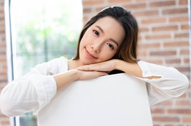 Bir sandalye restin oturmuş çekici ve hayret genç Asyalı kadın