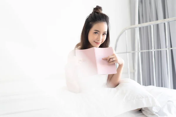 かわいいかわいい若いアジアの女性は、本を読んで、彼女のように微笑んで — ストック写真