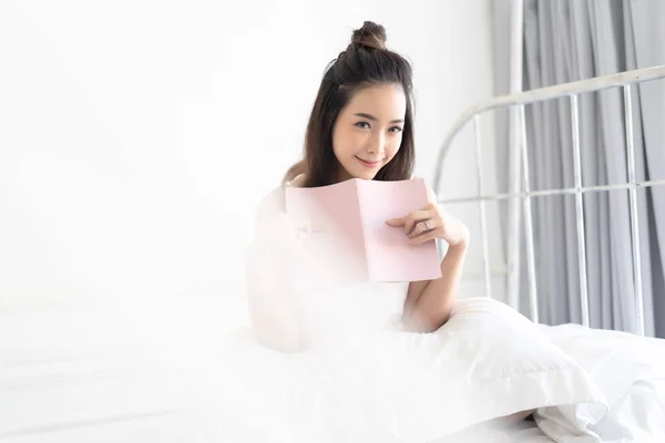 Cute lovely young Asian woman reading a book and smiling as she — Stock Photo, Image