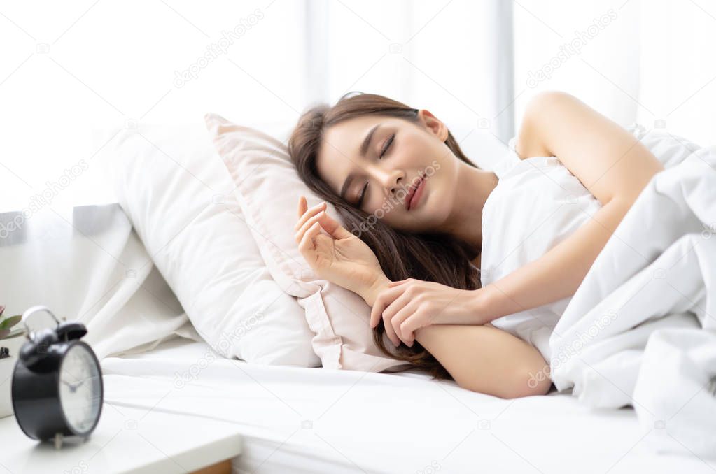 Side view of beautiful young Asian woman smiling while sleeping 