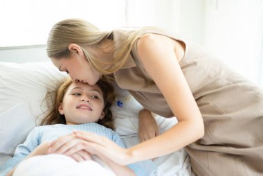 Hastanede yatakta yatan hasta çocuk kız ve anne eli h