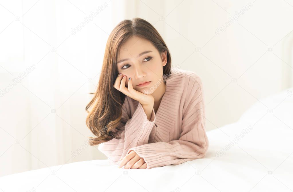 Woman indoor portrait. Closeup of pensive young Asain woman in w