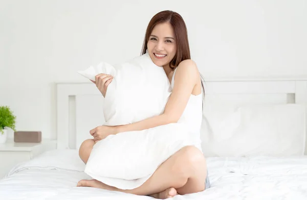 Positive asiatique femme assis étreignant oreiller dans lit et souriant t — Photo