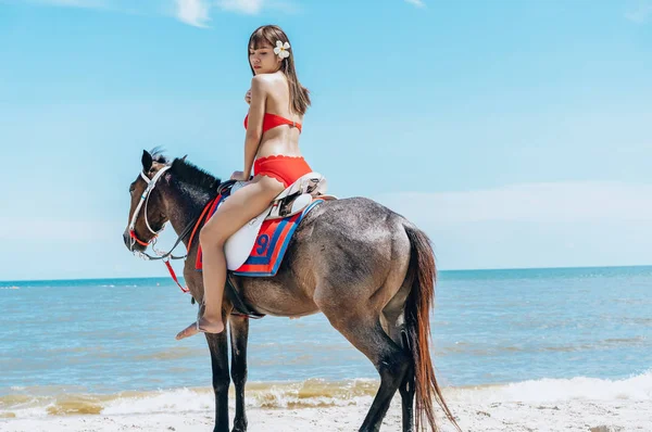 Ung asiatisk kvinna i röd bikini ridning häst på havet kusten Li — Stockfoto