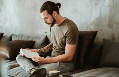 Okurken kafede oturan genç sakallı hipster portresi 