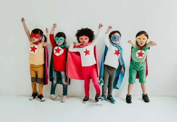 Group of Diverse Children Playing superhero on the white wall ba