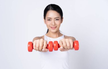 Spor yapan Asyalı kadın stüdyoda kameraya bakıyor.