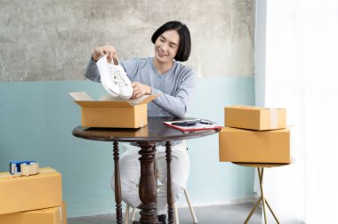 Genç serbest çalışan Asyalı adam Sho paketlerken internette iş yapıyor.