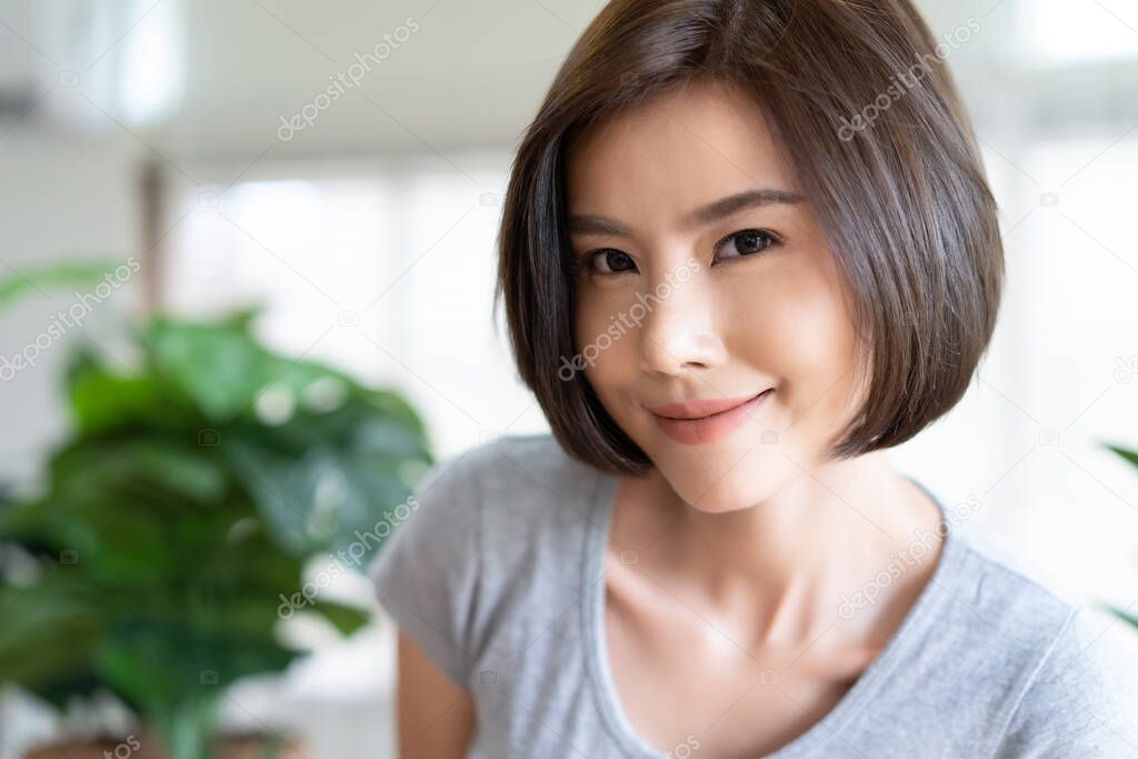 Portrait of happy young Asian girl taking a selfie in living room. Natural Beauty and Healthy Woman. People sincere emotions lifestyle concept.