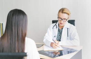 Orta yaşlı kadın doktor hastasına teşhisi açıklıyor. Tıp ve Sağlık Hizmetleri kavramı.