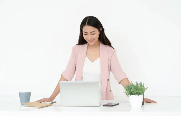 Portrait of young Asian casual woman working small business online owner standing at desk with laptop. Girl freelancer,entrepreneur works at home.Online marketing,education, e-learning, distance work.