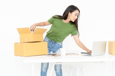 Genç Asyalı sıradan bir kadın çevrimiçi küçük işletmelerden karton kutuya ürün paketliyor. Başlangıç küçük işletme sahibi, çevrimiçi satış, e-ticaret, dağıtım, serbest çalışma..