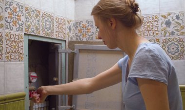 Genç ve güzel bir kadın bir dairede suyu kesiyor. Dağıtım manifoldunun top vanasını çevirmeye çalışıyor. Tamire ihtiyacı olan bir tesisatçı. Oda servisi.