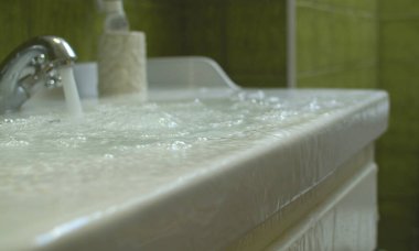 Banyodaki yerde taşan ve akan su. Lavabo tıkandı. Tamire ihtiyacı olan tesisat..