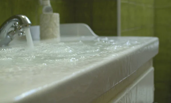Banyodaki yerde taşan ve akan su. Lavabo tıkandı. Tamire ihtiyacı olan tesisat..