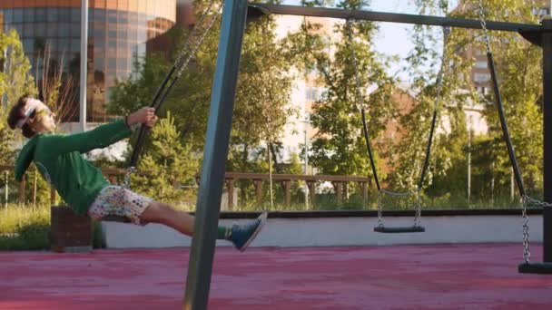 Engraçado aberração balançando em um balanço no parque infantil — Vídeo de Stock