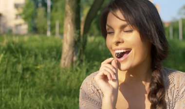 Kiraz yiyen güzel, gülümseyen bir kadının portresini yakından çek. Parktaki çimlerin üzerinde piknik. Rahatlama ve zevk