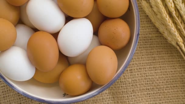 Huevos en un tazón y espigas de trigo — Vídeo de stock