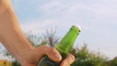 Erkek eli bira şişesini açıyor.