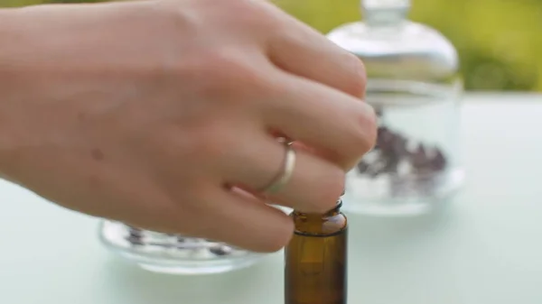 Eline kekik yağı damlatarak kapat. Masadaki cam kavanozlardaki enfeksiyonlar. Şifalı bitkiler. Doğal eczane ve aromaterapi konsepti. Kamerayla yakın çekim yap veya hareket ettir.
