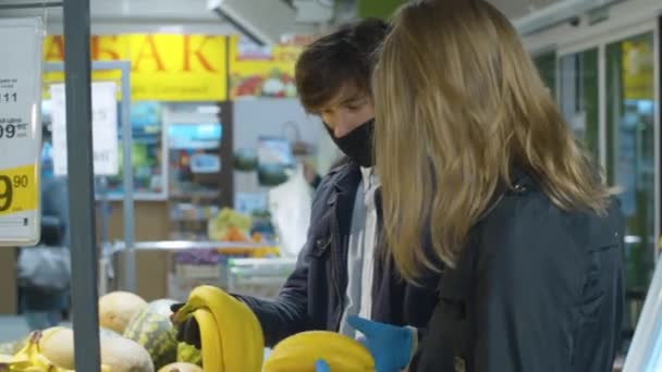 Ζευγάρι επιλέγει φρούτα στο σούπερ μάρκετ φορώντας προστατευτικές μάσκες — Αρχείο Βίντεο