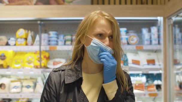 Jeune femme éternue dans un masque de protection dans un supermarché — Video