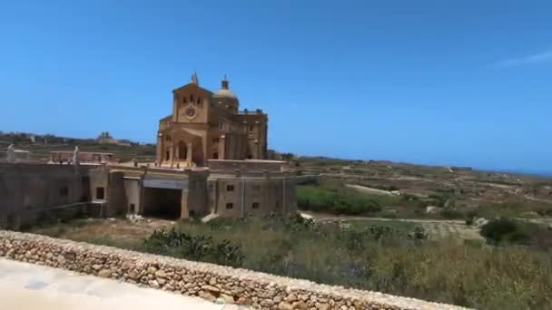 ヨーロッパのマルタの周りに緑のフィールドを持つ古い建築教会の周りに回転ショット — ストック動画