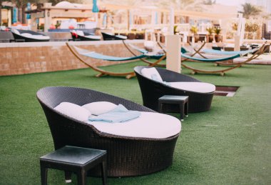 Oteldeki boş plaj şezlongları, sandalyeler ve hamaklar yeşil çimlerin üzerinde. Otellerde karantina