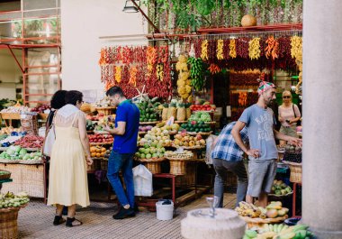Funchal - Madeira, 20.09.2019. Pazardaki müşteriler satıcıyla konuşuyor ve meyve tezgahına bakıyorlar..