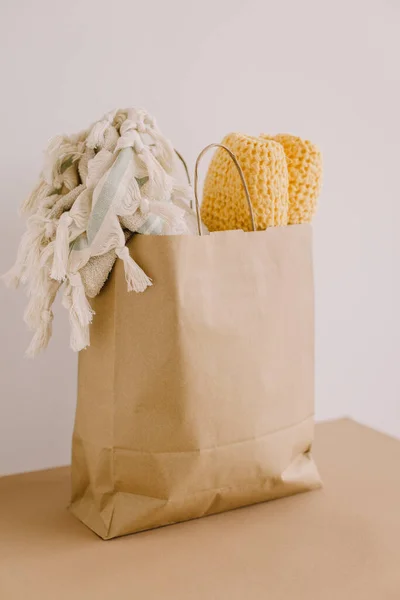 Paper bag with folded towels or a cloth on a white wall. Time to pack for the beach.
